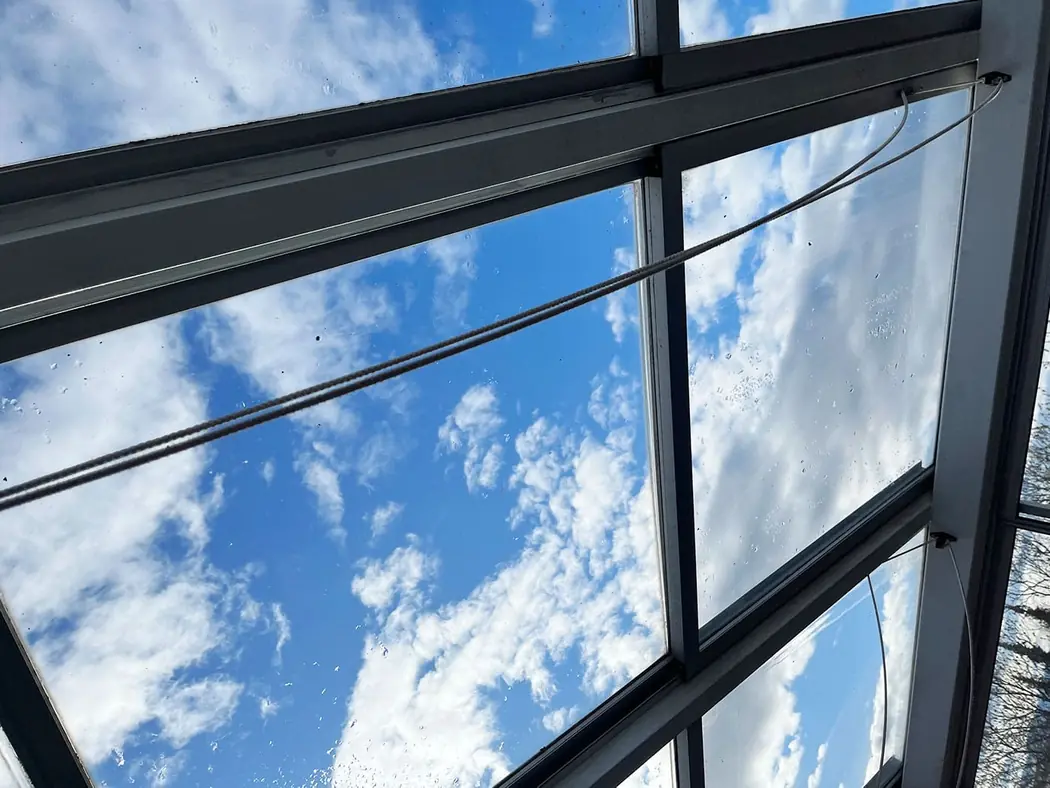 Det samme glasstaket etter vask, med klar blå himmel gjennom glasset