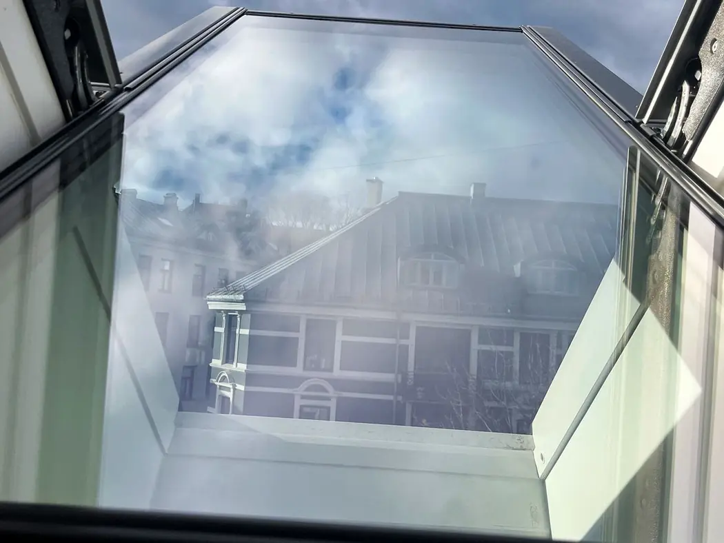 Det samme takvinduet etter vask, der nabohuset speiler seg klart i glasset